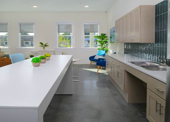 A kitchen with a white countertop and a blue chair.