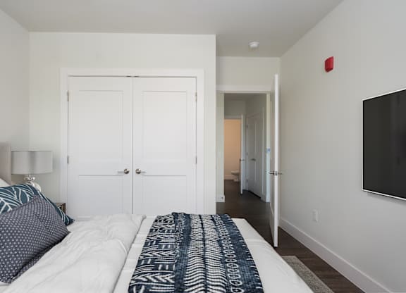 A bedroom with a bed, a lamp, and a television.