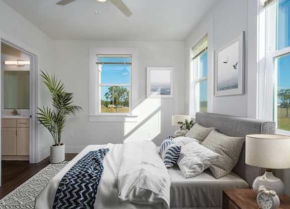 A bedroom with a bed, a ceiling fan, and a potted plant.