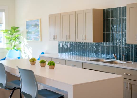 A kitchen with a white counter and blue chairs.