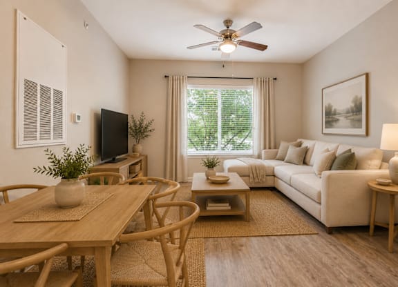 A living room with a wooden table and chairs, a couch, a television, and a painting on the wall.