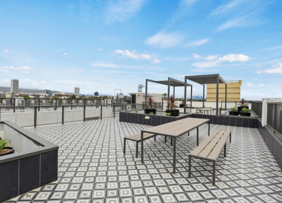 a roof deck with a picnic table and benches at The Fairfax Flats Apartments, Los Angeles, California