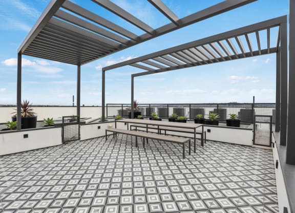 a view of the rooftop terrace of a building with a pergola and benches at The Fairfax Flats Apartments, Los Angeles, CA, 90019