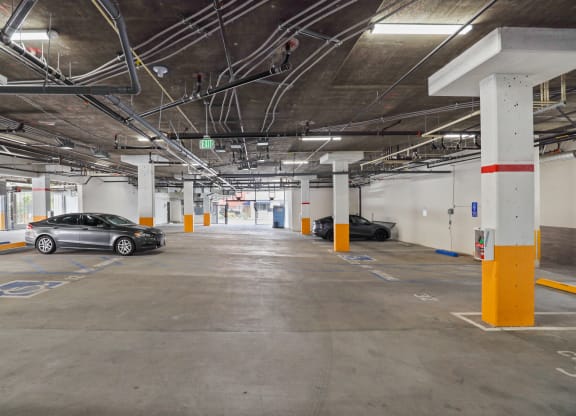 a parking garage with two cars parked on the left and one car on the right at The Fairfax Flats Apartments, Los Angeles, California