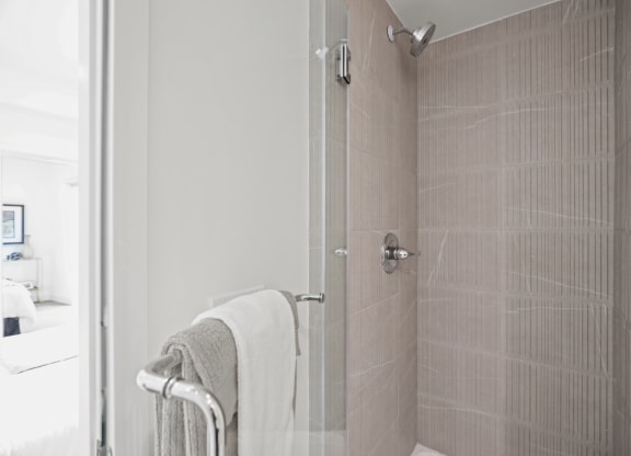 a bathroom with a shower and a towel rack at The Fairfax Flats Apartments, Los Angeles, CA