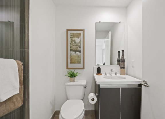 a small bathroom with a toilet sink and mirror at The Fairfax Flats Apartments, Los Angeles, CA
