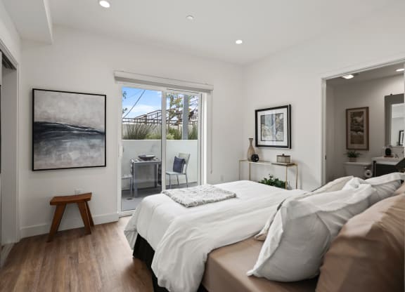 a bedroom with a bed and a door leading to a balcony at The Fairfax Flats Apartments, Los Angeles, CA, 90019