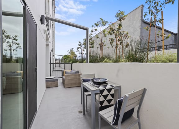 a small balcony with a table and chairs at The Fairfax Flats Apartments, Los Angeles, California
