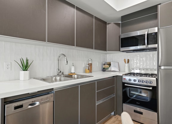 a kitchen with grey cabinets and a white counter top at The Fairfax Flats Apartments, Los Angeles, CA, 90019