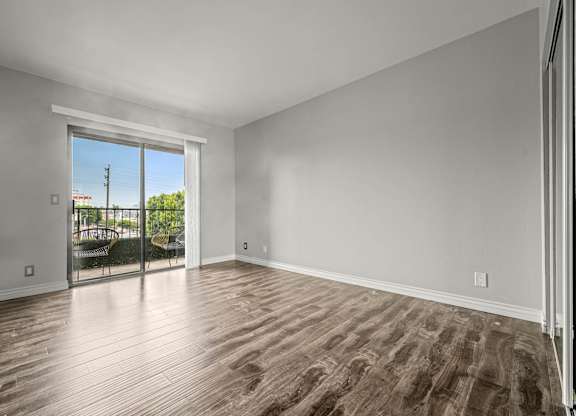 A room with wooden flooring and a sliding glass door leading to a balcony at Lafayette Apartments, California