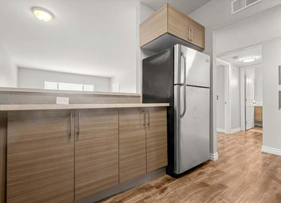 A modern kitchen with a black refrigerator and wooden cabinets at Lafayette Apartments, California, 90019