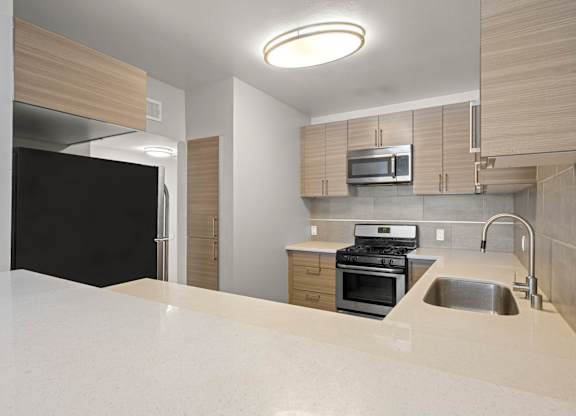 A modern kitchen with a black refrigerator and stove at Lafayette Apartments, Los Angeles, CA, 90019