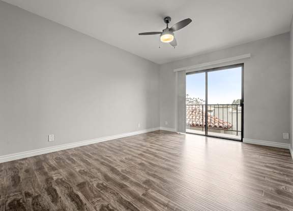 A room with a ceiling fan and sliding glass doors leading to a balcony at Lafayette Apartments, Los Angeles