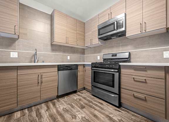A kitchen with wooden cabinets and black appliances at Lafayette Apartments, Los Angeles