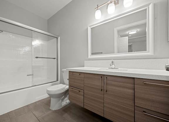 A bathroom with a toilet, sink, and mirror at Lafayette Apartments, California