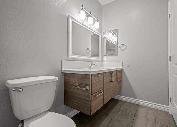 A bathroom with a toilet, sink, and mirror at Lafayette Apartments, Los Angeles 90019