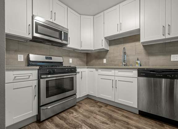 A modern kitchen with white cabinets and stainless steel appliances at Lafayette Apartments, Los Angeles
