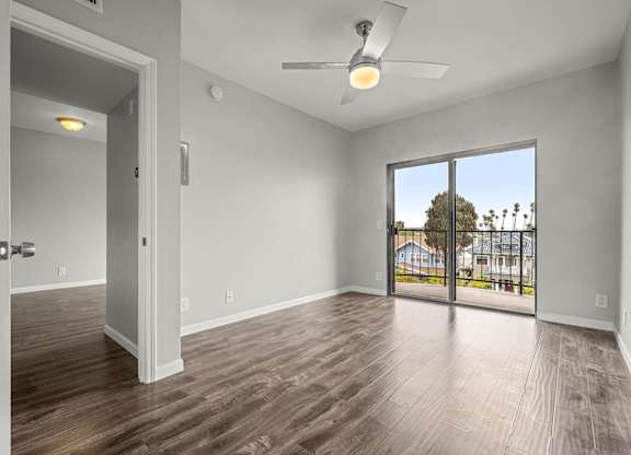 A room with a ceiling fan and sliding glass doors leading to a balcony at Lafayette Apartments, Los Angeles, CA, 90019