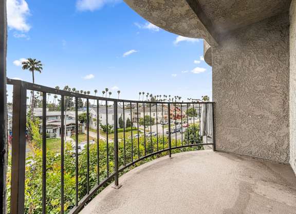 A balcony with a metal railing overlooks a residential area. at Lafayette Apartments, Los Angeles, CA