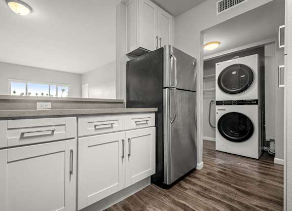 A modern kitchen with a black fridge and a washing machine at Lafayette Apartments, California, 90019