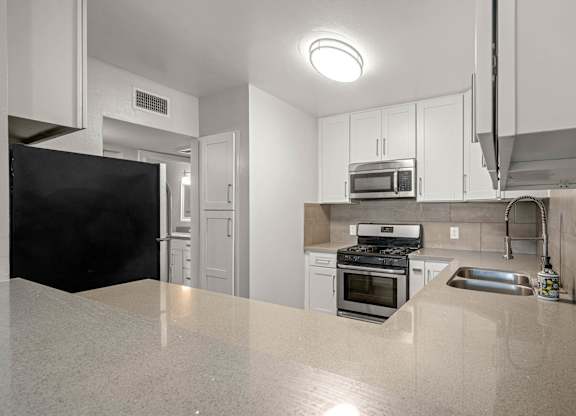A kitchen with white cabinets and stainless steel appliances at Lafayette Apartments, Los Angeles, California