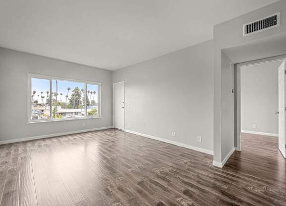 A room with wooden flooring and a large window overlooking a cityscape at Lafayette Apartments, Los Angeles, CA