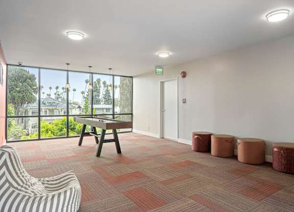 A room with a striped chair, a wooden table, and four stools at Lafayette Apartments, Los Angeles, CA