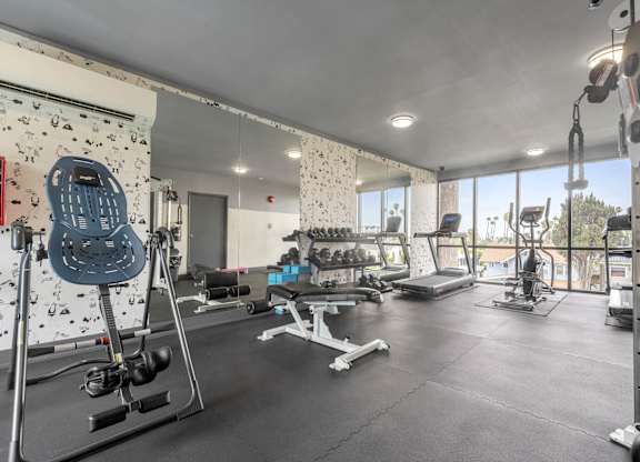 A spacious gym with a variety of equipment including a leg press machine at Lafayette Apartments, Los Angeles, CA, 90019