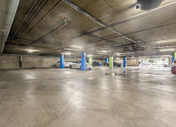 A parking garage with a concrete floor and multiple cars parked at Lafayette Apartments, California, 90019