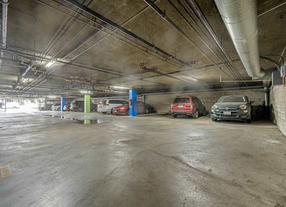 A parking garage with a few cars and a blue wall at Lafayette Apartments, Los Angeles, California