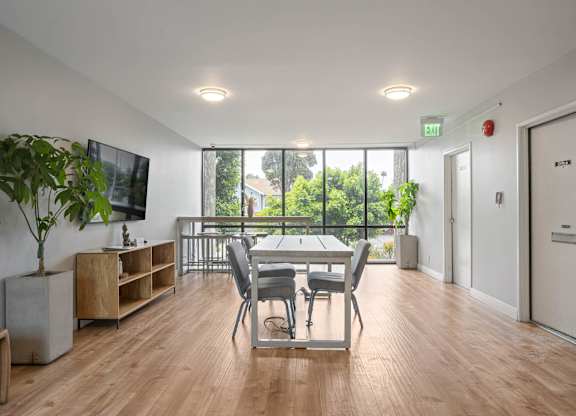 A room with a wooden floor and a large window with a view of trees at Lafayette Apartments, California, 90019
