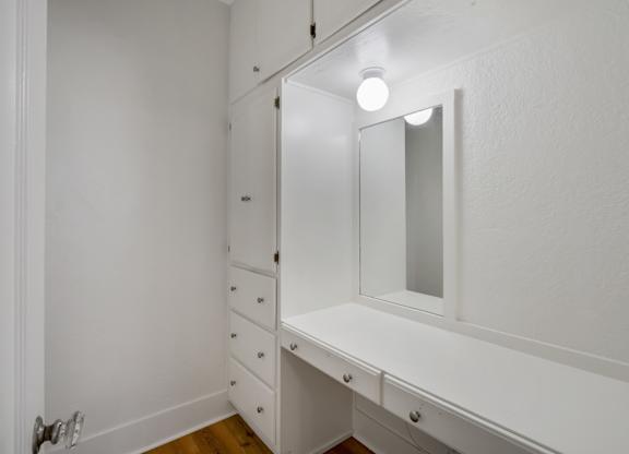 White bathroom with a vanity and mirror at The Langham Apartments, California, 90005