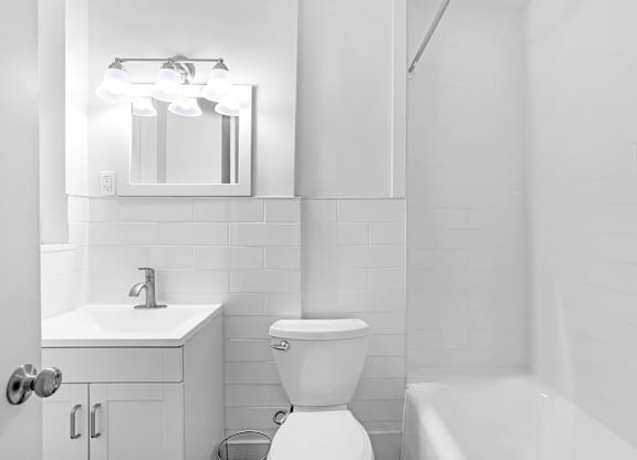 A white bathroom with a toilet, sink, and mirror.at Park Wilshire, California, 90057
