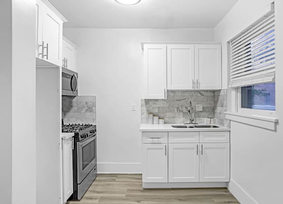 A kitchen with white cabinets and a marble backsplash.at Park Wilshire, Los Angeles California