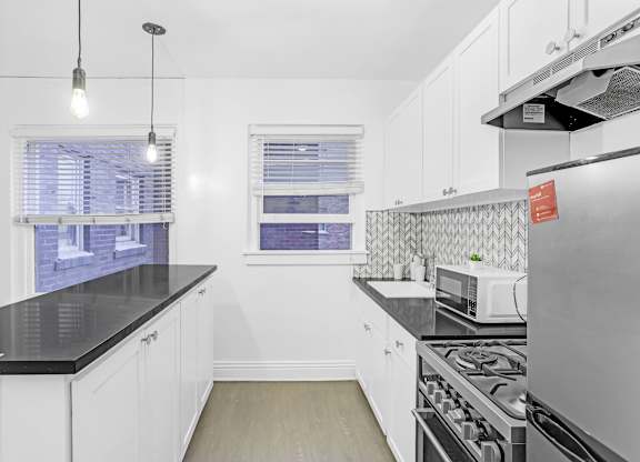 A kitchen with white cabinets and a black countertop.at Park Wilshire, Los Angeles California