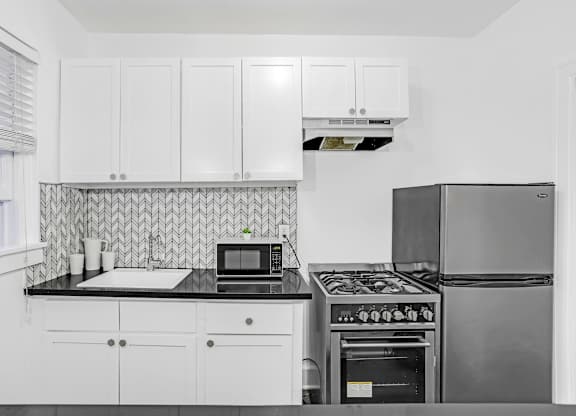 A kitchen with white cabinets and a black stove top.at Park Wilshire, California