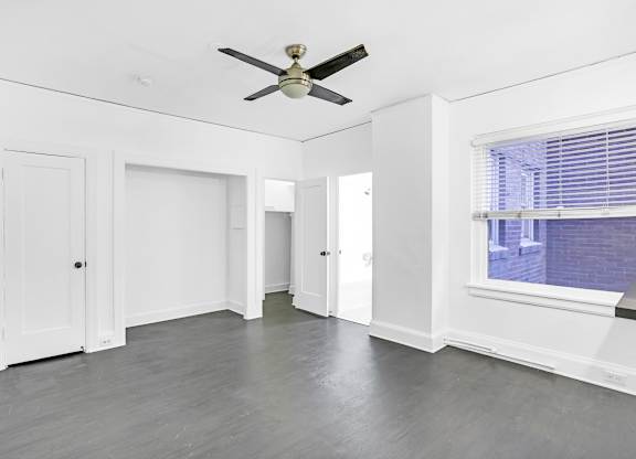A room with a ceiling fan and a window with blinds.at Park Wilshire, Los Angeles