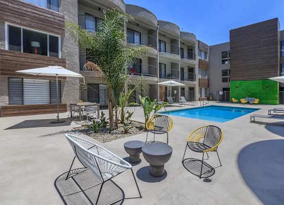 A pool area with a white chair and a yellow chair at Lafayette Apartments, California, 90019