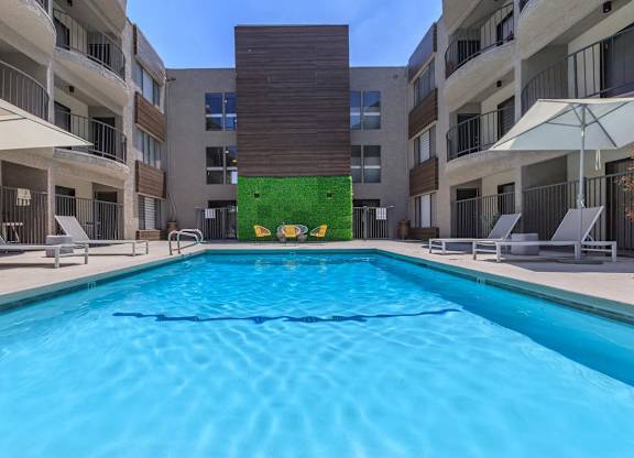 A swimming pool in front of a building with a green wall at Lafayette Apartments, Los Angeles, CA, 90019