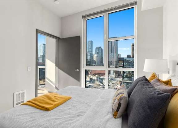 A bedroom with a large bed and a view of the city through the window.