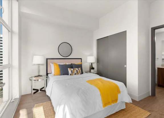 A bedroom with a white bed and yellow throw.
