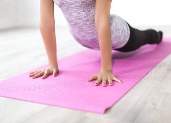A person is doing a plank exercise on a pink yoga mat.