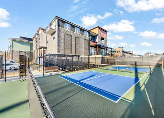 A tennis court is located in front of a building.