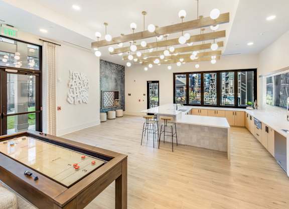 A room with a pool table and a kitchen area.