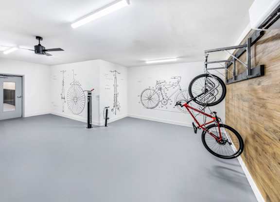 A room with a bicycle hanging on the wall and a fan on the ceiling.