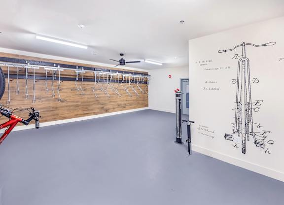 A bike is parked in a room with a wall drawing of a bike.