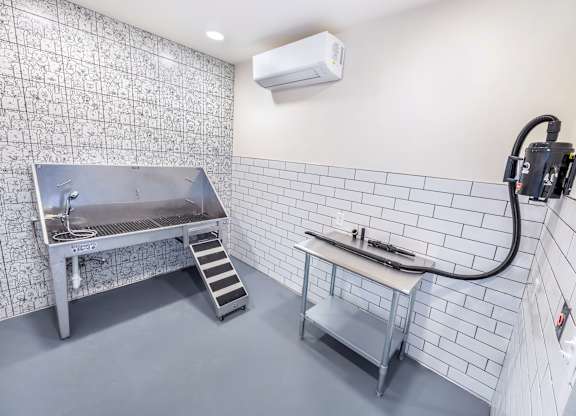 A kitchen with a stainless steel sink and a white tile wall.