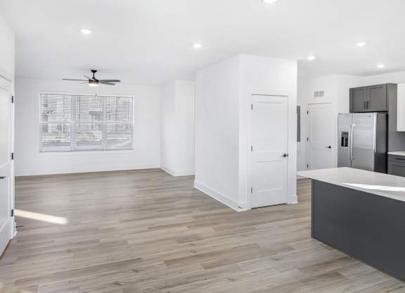 A spacious kitchen with a ceiling fan and wooden flooring.