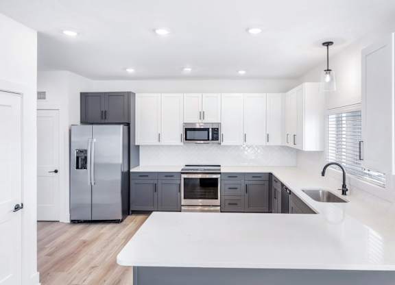 A modern kitchen with a white countertop and stainless steel appliances.