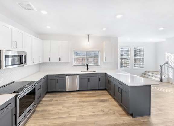 A modern kitchen with wooden floors and white cabinetry.